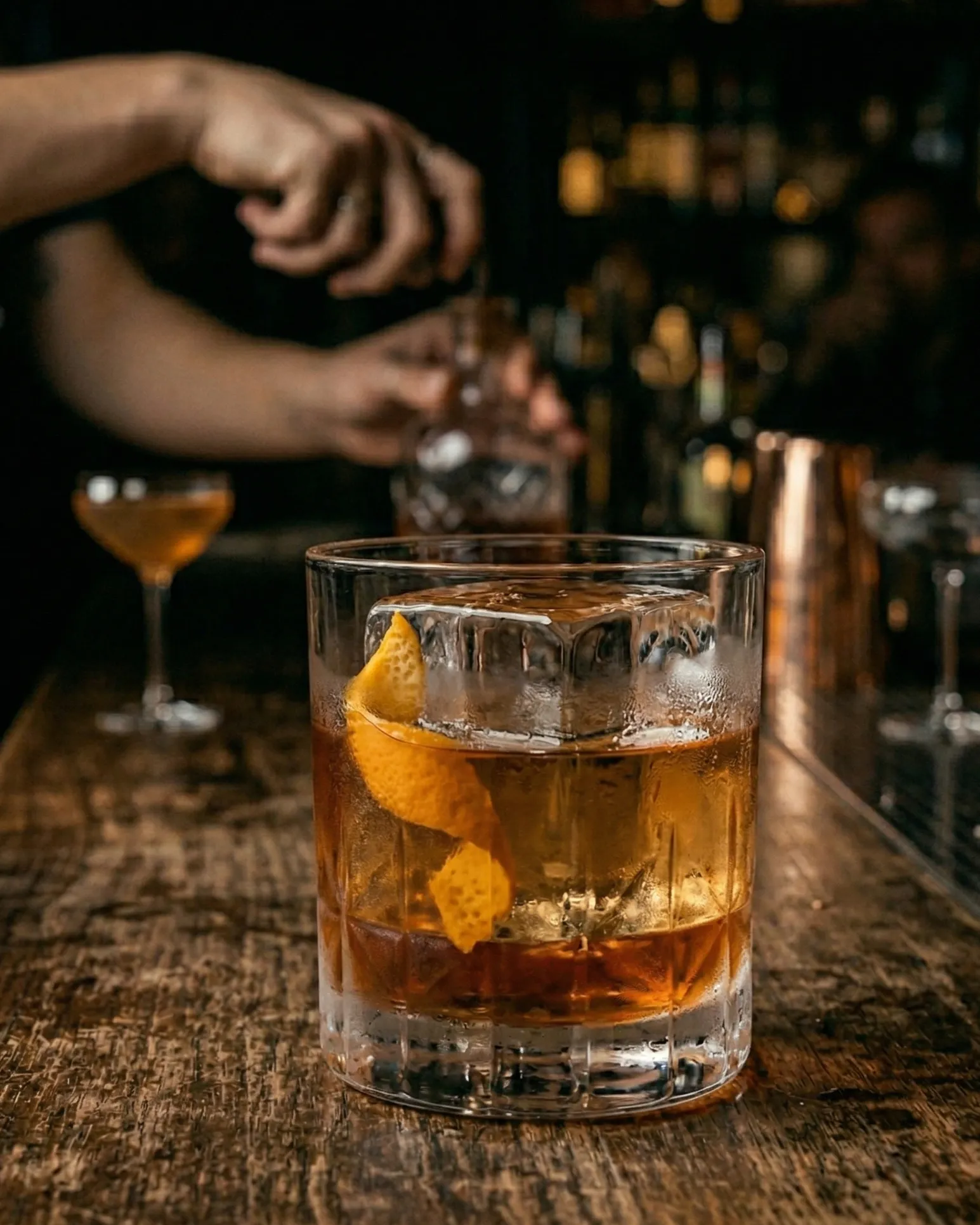 An Old Fashioned served over a single large clear ice cube in a rocks glass
