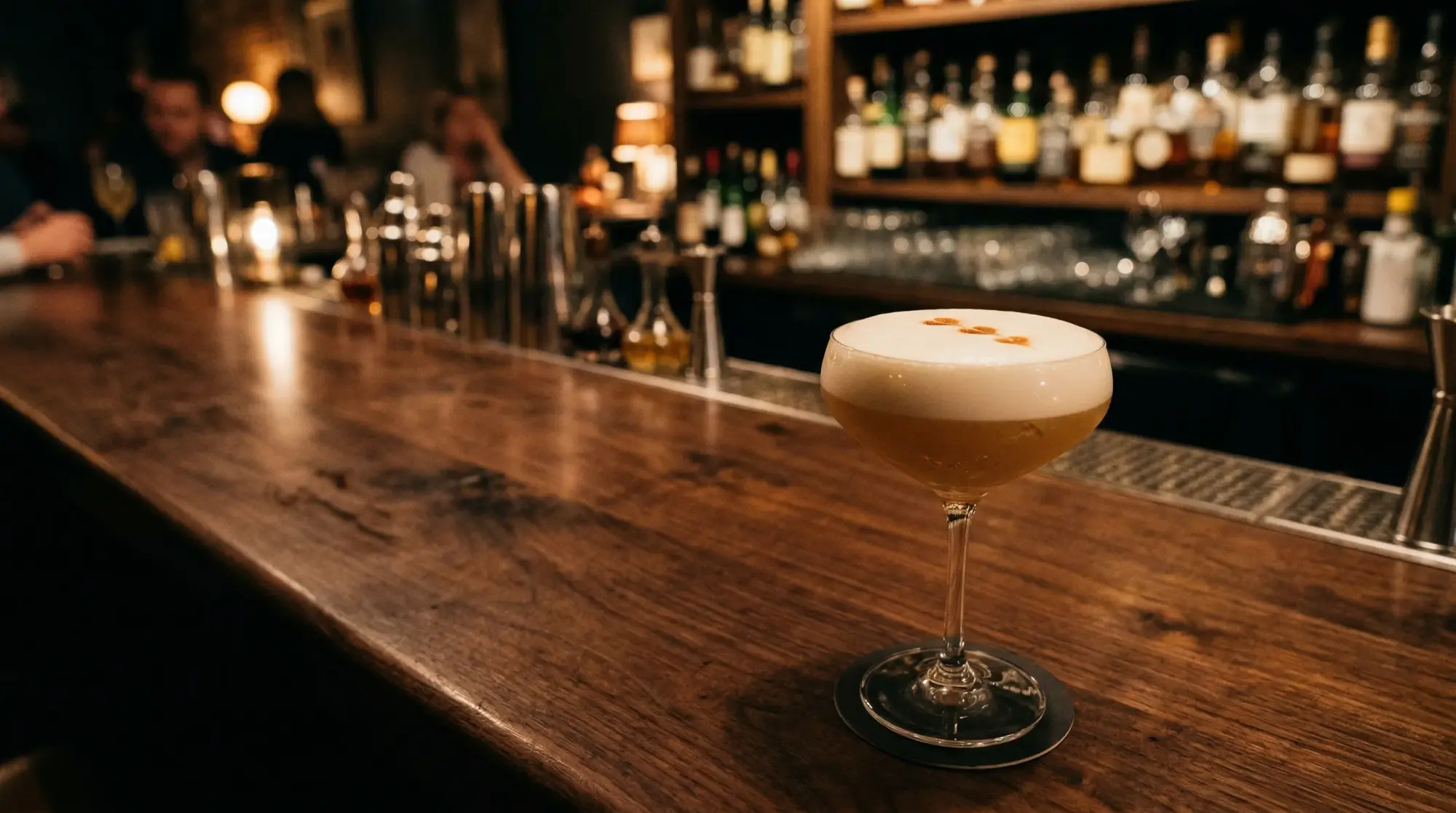 A whiskey sour with a thick egg white foam cap on a wooden bar