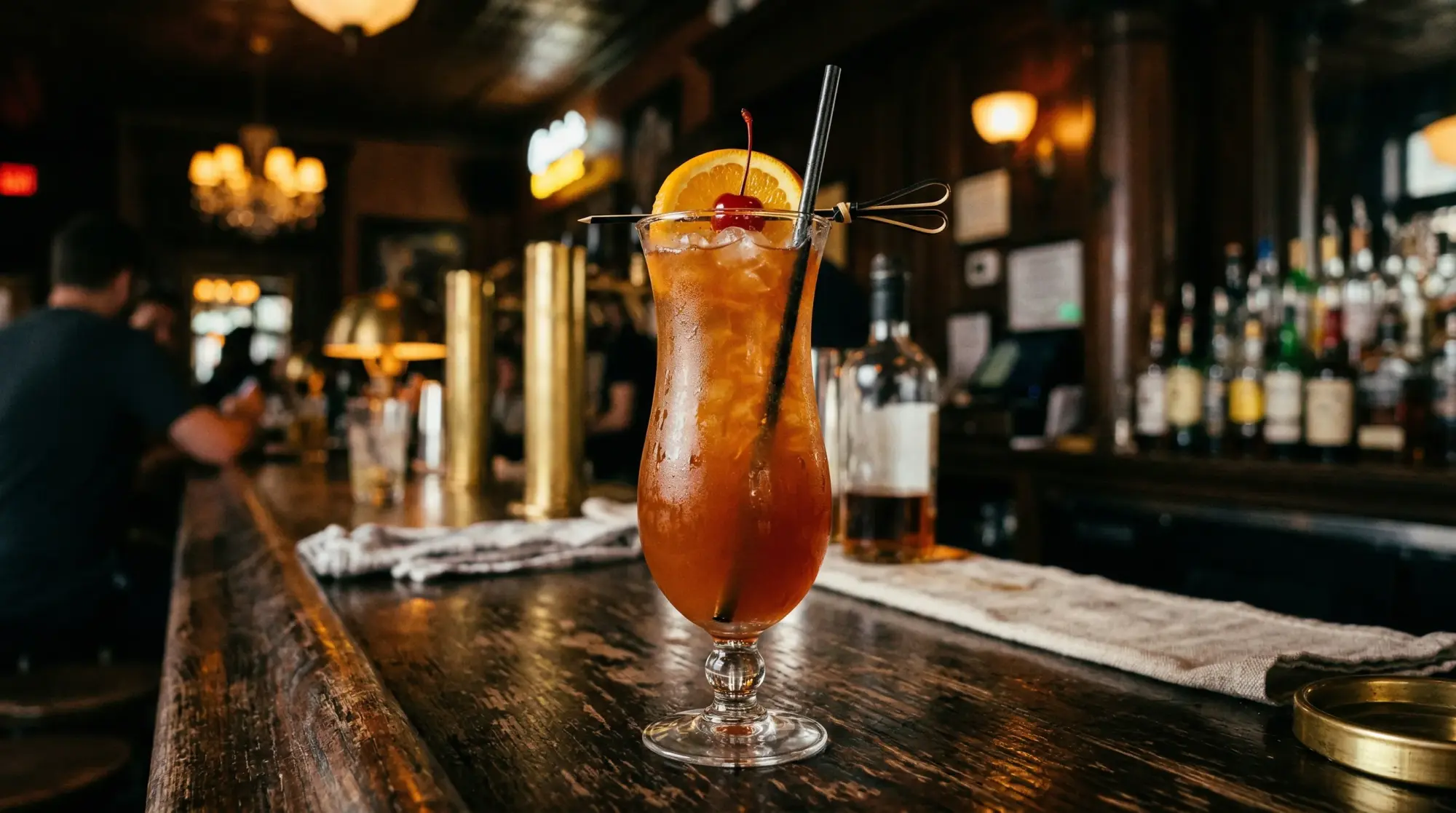 Hurricane cocktail in a hurricane glass with orange slice and cherry garnish
